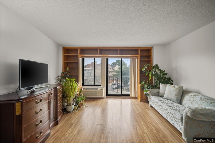 Living room with light wood-style floors, a textured ceiling, and a wall of windows