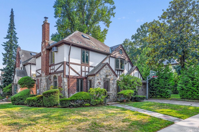 Tudor-style house featuring stucco siding, a chimney, and stone siding