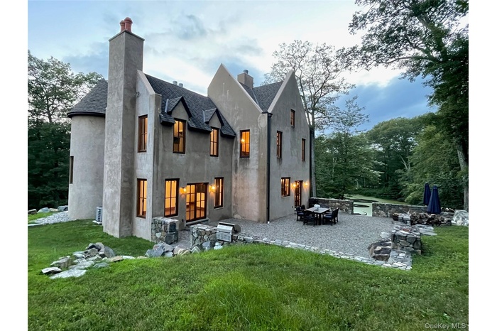 Back of property featuring a chimney, a patio, and roof with shingles