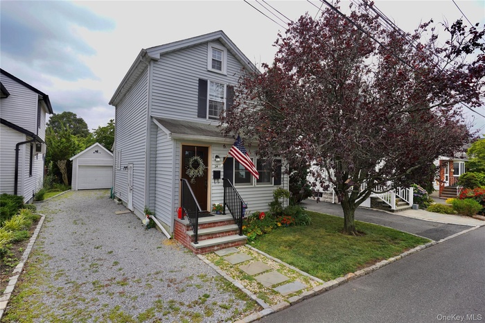 View of front of property with an outdoor structure, driveway, entry steps, and a detached garage