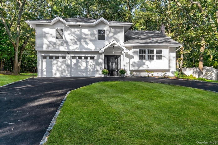 Split level home featuring driveway and view of wooded area