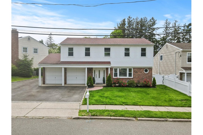 View of front facade featuring brick siding, asphalt driveway, and roof with shingles