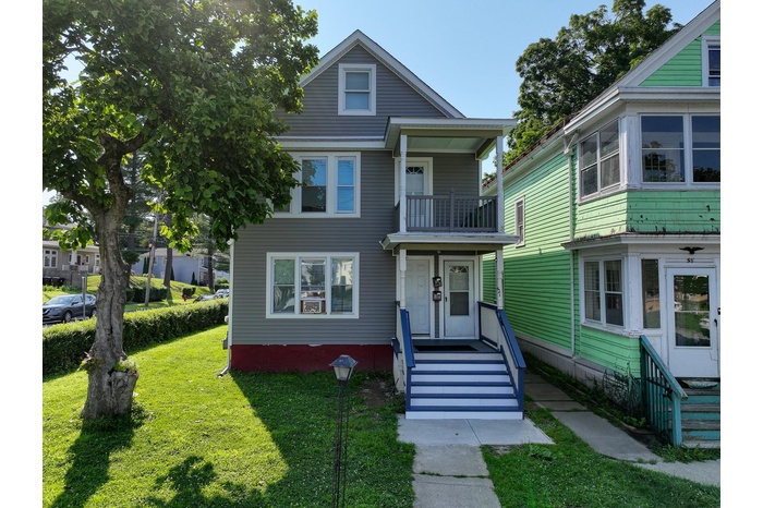 View of front facade with a front yard and a balcony