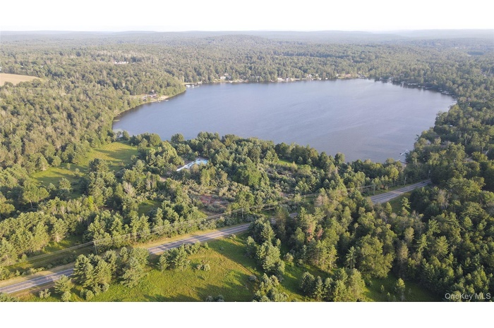 View of property location with a forest and a nearby body of water