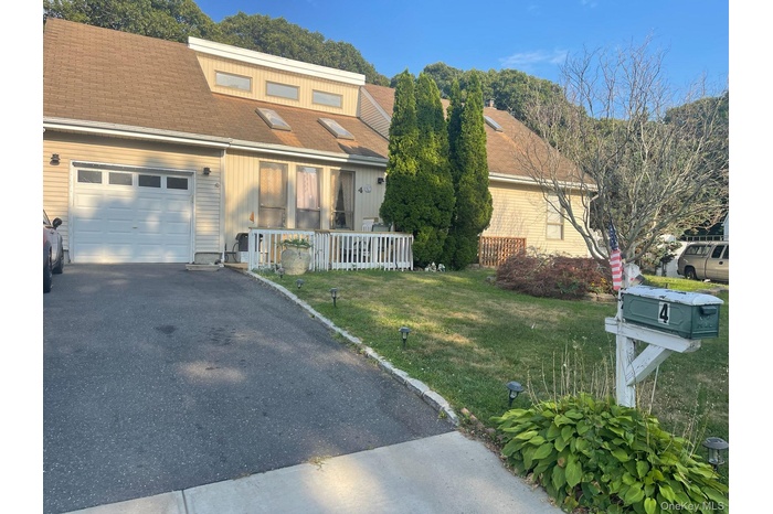 View of front of property featuring a porch, a front yard, a garage, driveway, and a shingled roof