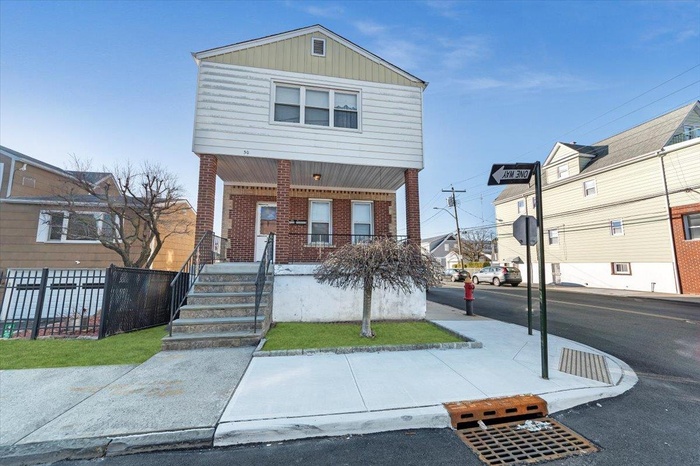 View of front of house featuring brick siding, a porch, and fence