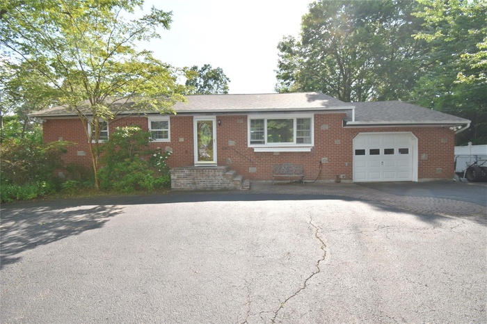 Ranch-style house with driveway, a garage, and brick siding