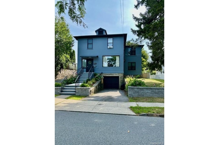 View of front of property featuring stucco siding, a garage, asphalt driveway, stone siding, and stairs