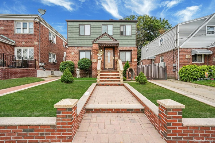 View of front of home with a gate and brick siding