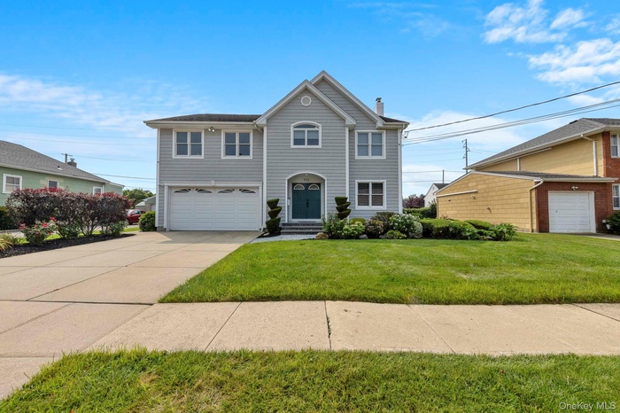 View of front of house featuring a garage, a chimney, driveway, and a front lawn