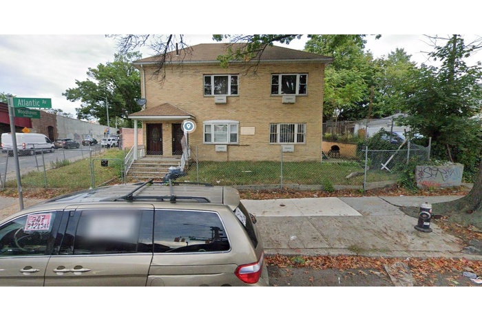 View of front of house featuring brick siding, a front yard, and fence