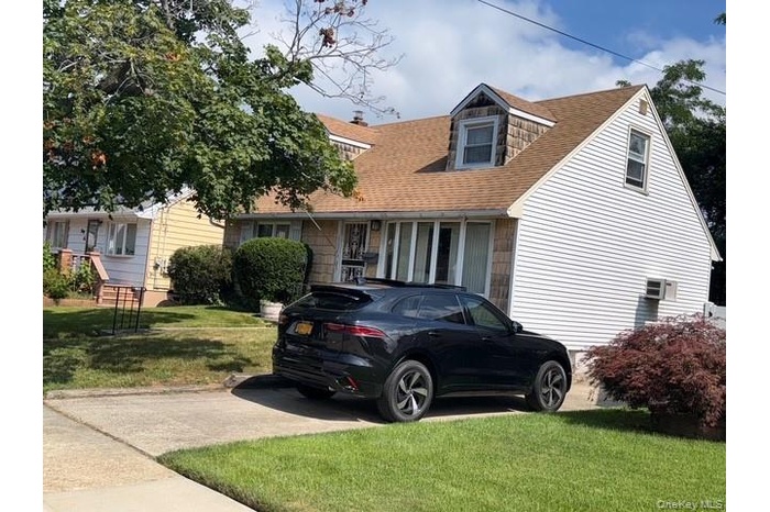 Cape cod home with a front lawn and a shingled roof