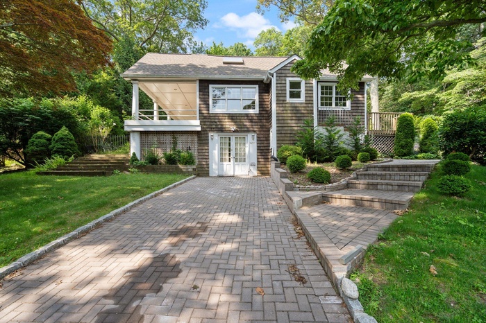 Shingle-style home featuring french doors, a front yard, and a shingled roof