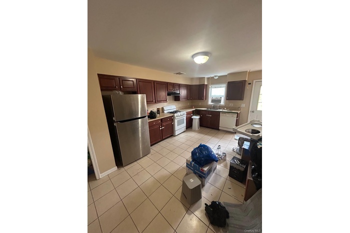 Kitchen featuring light tile patterned floors, white appliances, light countertops, dark brown cabinetry, and under cabinet range hood