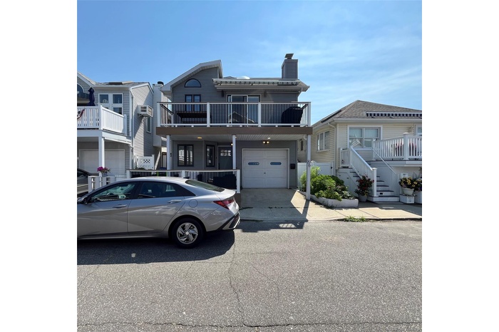 View of front of property with a balcony, a garage, a chimney, and concrete driveway