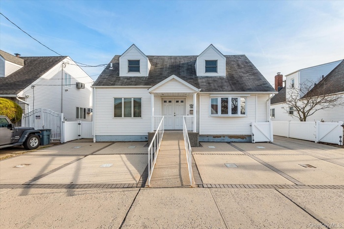 Cape cod home featuring a gate and a shingled roof
