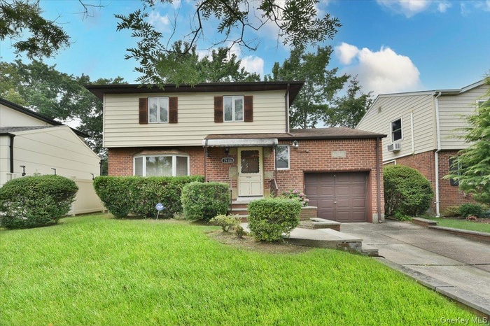 View of front of property with concrete driveway, brick siding, a front lawn, and an attached garage