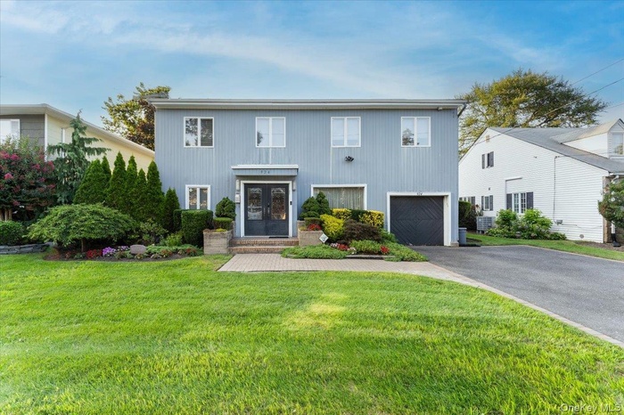 View of front of property with driveway, a front yard, and an attached garage
