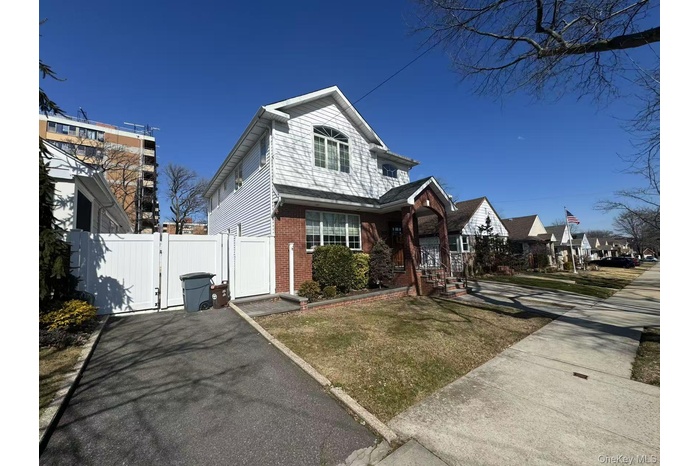View of front of home with a gate and brick siding
