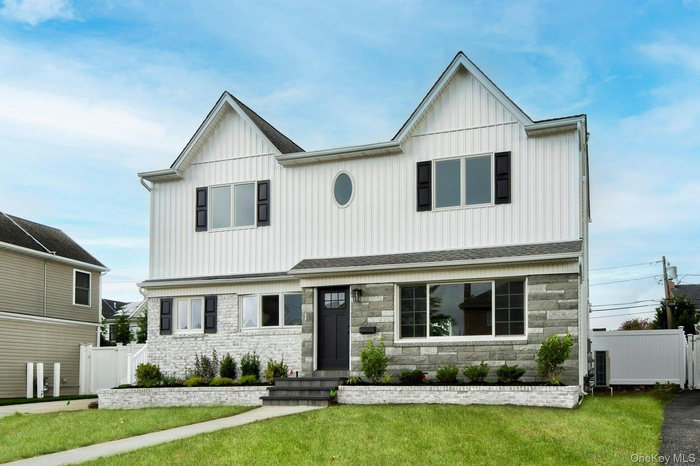 View of front facade with stone siding, board and batten siding, and a shingled roof
