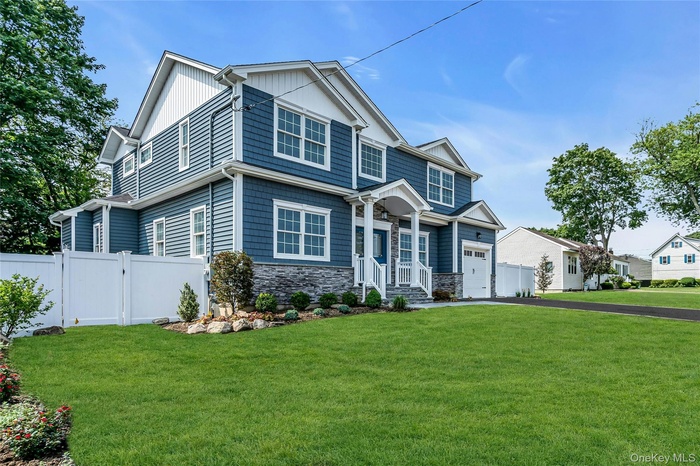 Craftsman-style home with stone siding, driveway, a gate, and an attached garage