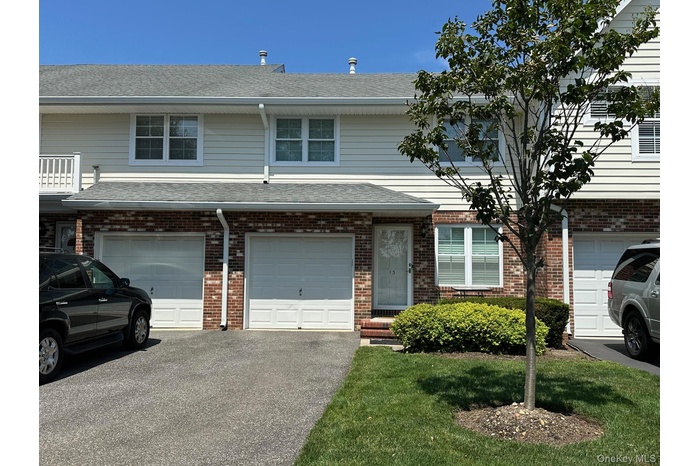 Traditional-style home with a shingled roof, driveway, an attached garage, and brick siding