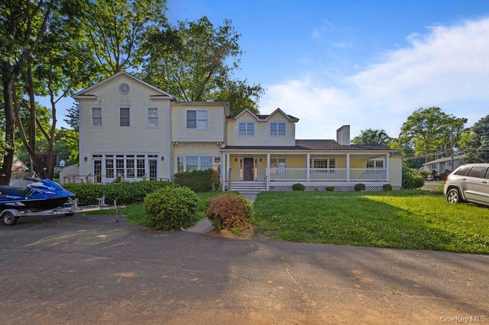View of front facade featuring a porch, a front lawn, and a chimney