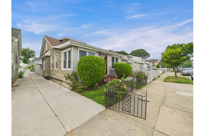 View of front of property featuring stone siding, a garage, and a residential view