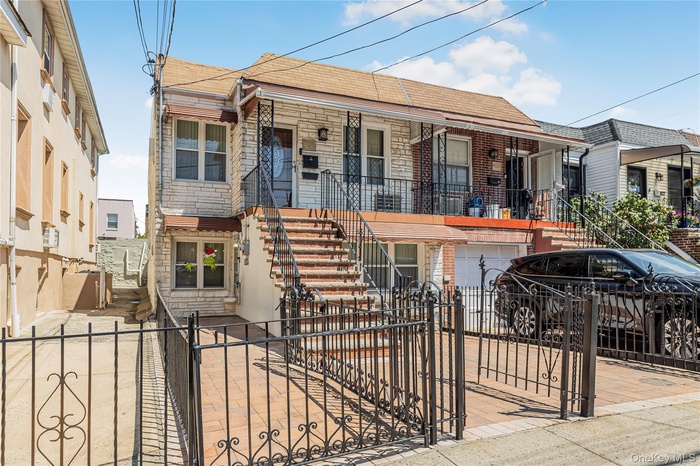 View of front of home featuring stairway, a gate, a fenced front yard, and stone siding