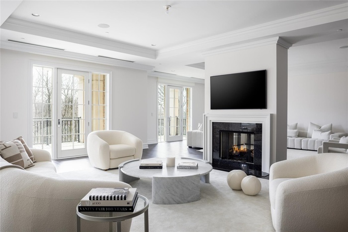 Living area featuring ornamental molding, a tray ceiling, recessed lighting, and a premium fireplace