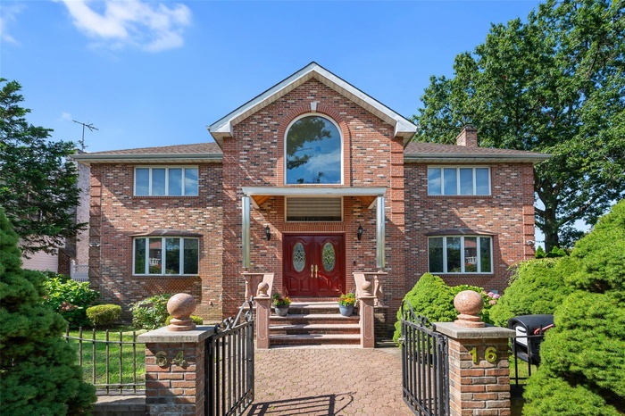 Traditional home featuring a fenced front yard, brick siding, and a gate