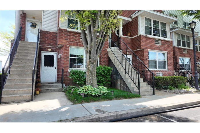 View of front facade featuring stairway and brick siding
