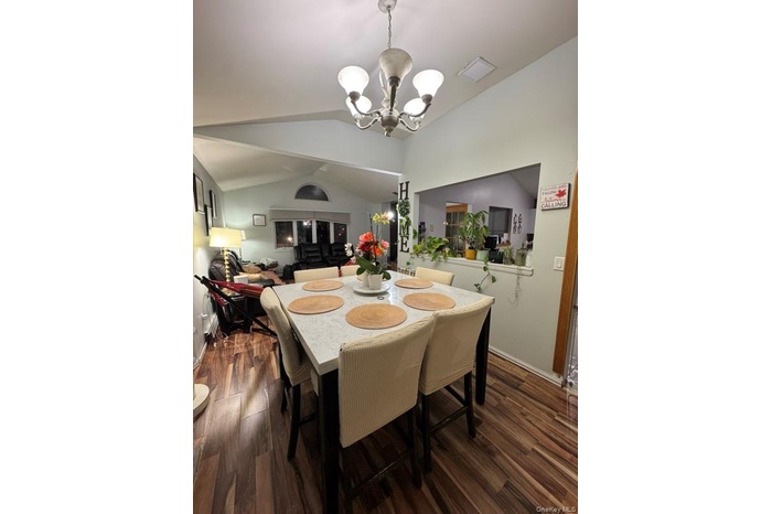Dining room with vaulted ceiling, dark wood finished floors, and a chandelier