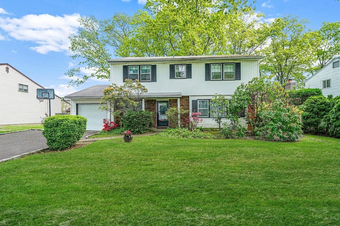 View of front of property with a garage, a front yard, driveway, and brick siding