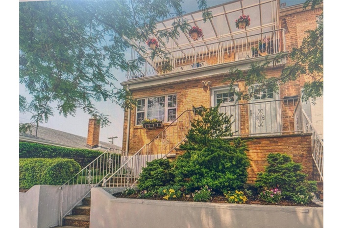 View of front facade with stairway, brick siding, and a balcony