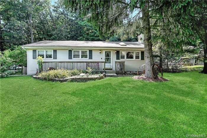 Single story home with a front lawn and a wooden deck