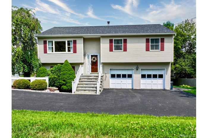Split foyer home with a garage, driveway, and roof with shingles