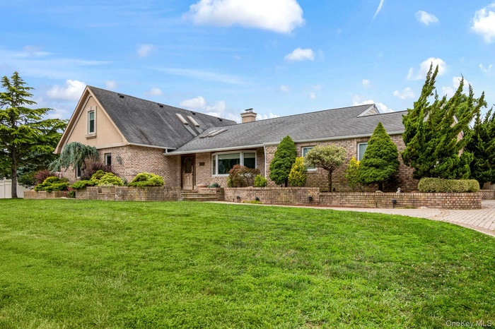View of front facade with brick siding, a shingled roof, and a front yard