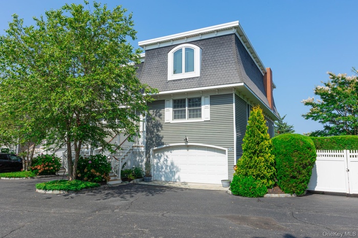 View of front of property with mansard roof, driveway, and an attached garage