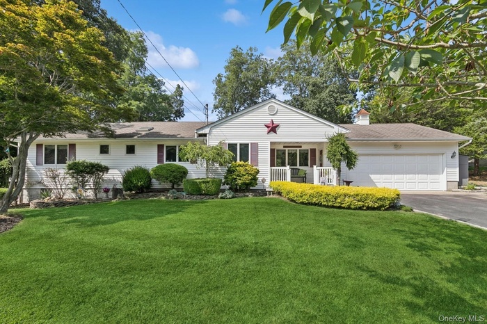 Single story home with driveway, an attached garage, a front yard, and a chimney