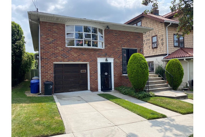 View of front facade featuring an attached garage, concrete driveway, and brick siding