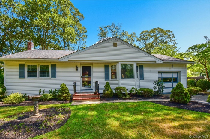 Ranch-style house with a garage, a front lawn, a chimney, and a shingled roof