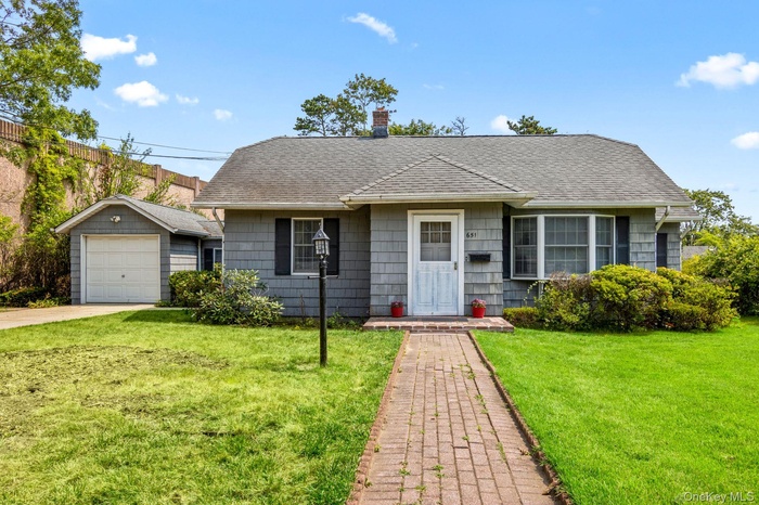 View of front of property featuring a shingled roof, a chimney, a breezeway to the garage, and a front lawn.