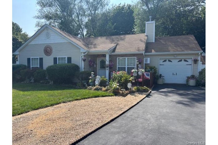 View of front of house with a garage, asphalt driveway, a chimney, and a front yard