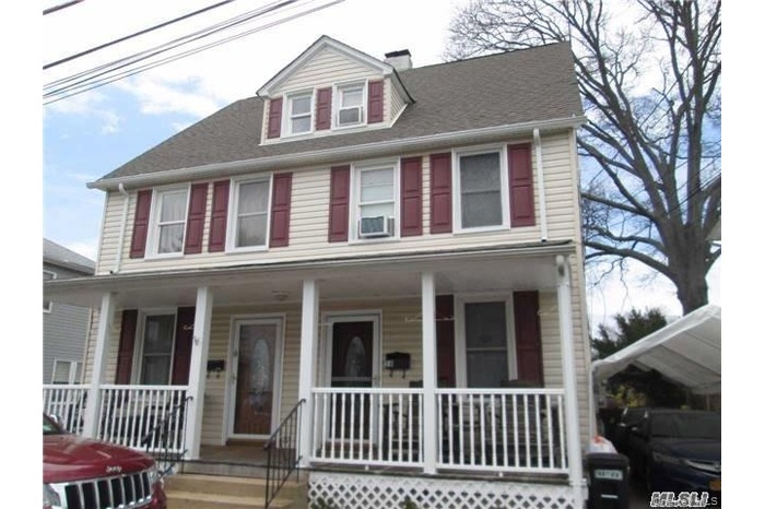 View of front of home featuring a porch, a shingled roof, and a chimney