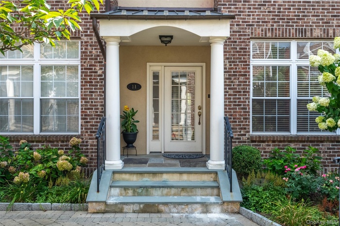 Doorway to property with brick siding, stucco siding, and a porch