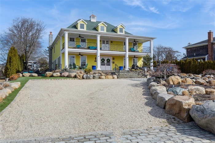 View of front of house with a balcony, a ceiling fan, driveway, and covered porch
