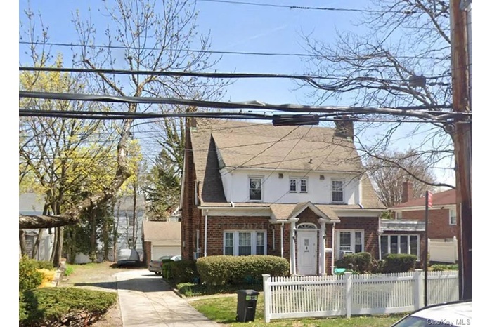 View of front of house with a chimney, a fenced front yard, and brick siding
