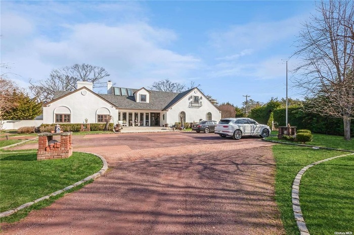 View of front of house with a front lawn, uncovered parking, a chimney, and stucco siding