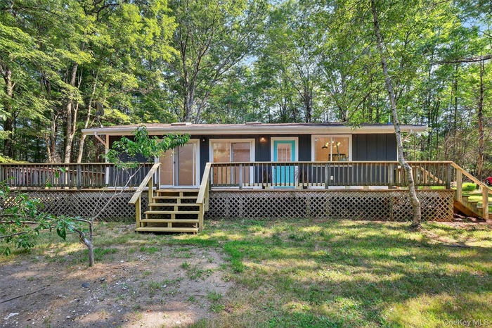 View of front of property featuring stairway, view of wooded area, a wooden deck, and board and batten siding